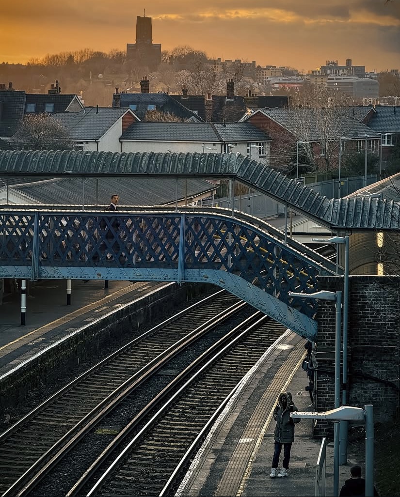 Pedestrian footbridge over railway tracks at a UK train station at sunset